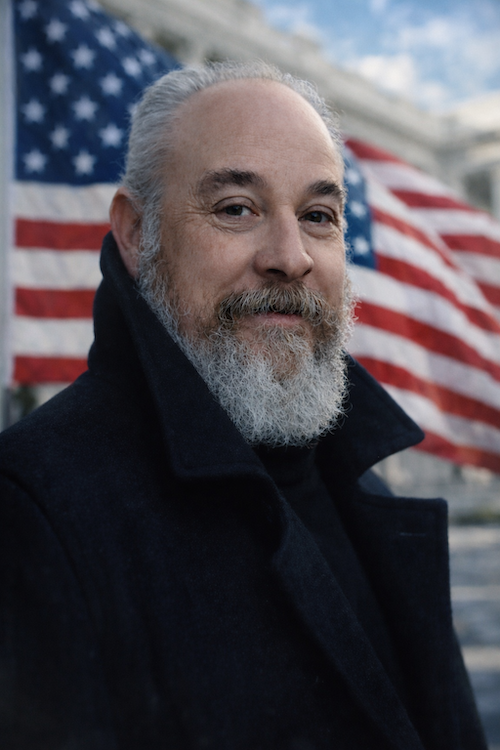 Lance Olive with an American flag in the background.